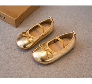 Vista detallada de los zapatos de princesa dorados para niñas con un lazo fino.