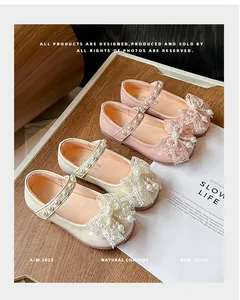 Close-up of elegant girls shoes showing delicate lace bows and pearl strap details