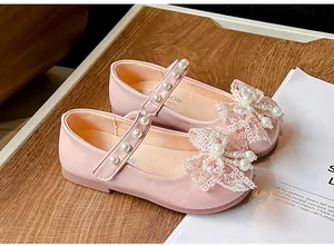 Close-up detail of pink girls' princess shoes with lace bow and pearl embellishments