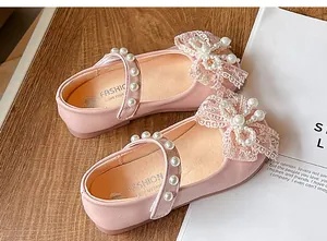 Close-up of girls' pink princess shoes with lace bows and elegant pearl decorations.