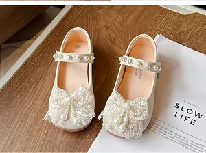 Close-up of girls' beige princess shoes with elegant lace bows and pearl accents