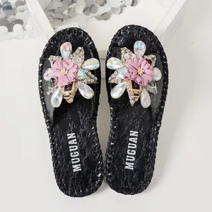 Gros plan de mules noires avec fleurs en tissu rose et pétales en strass irisés étincelants