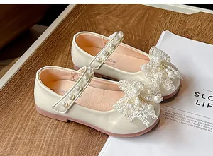 Close-up of elegant cream girls' Mary Jane shoes with delicate lace bows and pearls.