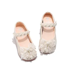 Close-up detail of sweet girls' princess shoes with lace bow and pearl embellishments
