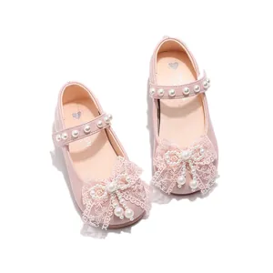 Detail showing pink girls Mary Jane shoes with large lace bow and pearl accents.