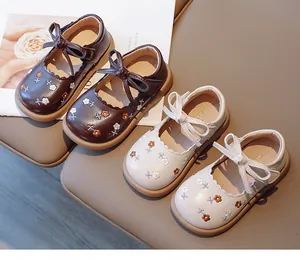Détail de chaussures de princesse brodées pour filles avec motifs floraux et nœuds.