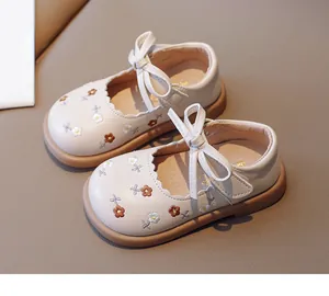 Gros plan de chaussures en cuir crème pour bébé fille avec broderie florale et nœud