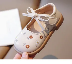 Gros plan d'une chaussure Mary Jane beige pour bébé avec broderie florale et petit nœud