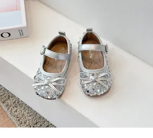 Nahaufnahme silberner Mädchen-Prinzessinenschuhe mit Pailletten, Schleife und Riemen.