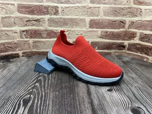 Vista detallada de zapatillas rojas transpirables de punto fly-knit para hombre sobre madera