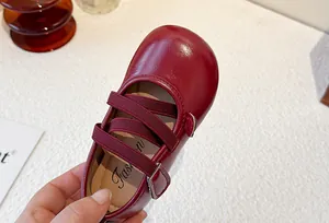 Close-up detail of red glossy leather girl's Mary Jane shoes with elastic cross straps