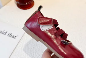 Close-up detail showing the glossy red leather and elastic straps of girls princess shoes