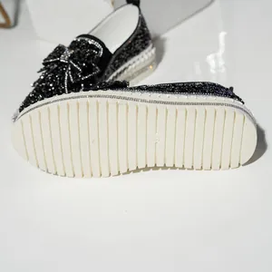 Detail of non-slip sole and rhinestone bow on black thick-soled loafers
