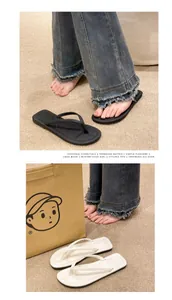 Detailansicht von modischen Zehenstegsandalen in Schwarz und Weiß auf Teppich