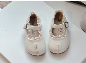 Primer plano de zapatos de cuero crema para niña con detalle de encaje fino