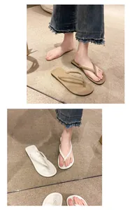 Detailaufnahme von minimalistischen flachen Damen-Zehentrennern in Beige und Weiß auf Teppich