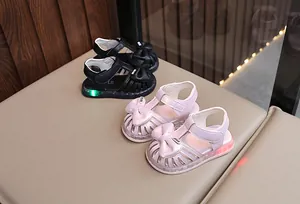 Nahaufnahme von Kleinkindmädchen-Sandalen mit Schleifen und LED-Licht in Pink und Schwarz.