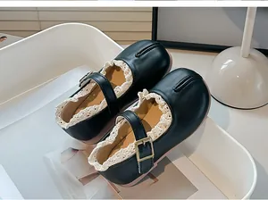 Detalle de zapatos Mary Jane Tabi negros para niña con ribete de encaje blanco.
