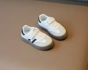 Detailansicht weißer Kinderschuhe mit schwarzen Streifen und Klettverschluss-Design