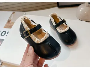 Detalle de zapatos Mary Jane negros para niña con punta dividida y borde de encaje.