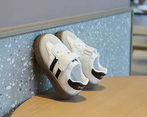 Detaillierte Nahaufnahme weißer Kleinkinder-Sneaker mit schwarzen Streifen und Klett