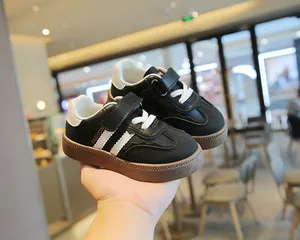 Nahaufnahme von schwarz-weißen Kinder-Sneakern im German Trainer-Stil mit Klettverschluss