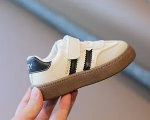 Nahaufnahme der weiß-schwarzen Kinder-German-Trainingssneaker mit brauner Sohle