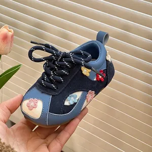 Close-up detail of navy blue toddler walking shoe with colorful floral embroidery