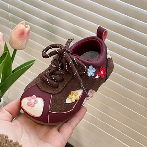 Close-up of brown and maroon toddler sneakers with colorful floral applique details.