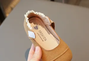 Detail der braunen Wildleder-Prinzessinenschuhe für Mädchen mit Spitzenborte und Klettverschluss