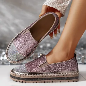 Primo piano di mocassini con plateau glitterati rosa con punta in strass e cuciture.