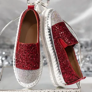 Vista dettagliata di mocassini rossi glitterati con punta in strass e suola platform