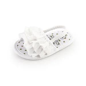 Detail of white ruffled baby walking sandal with elastic strap and polka dot insole