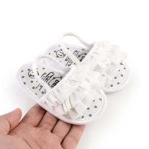 Detail view of white baby pre-walker shoes with ruffles being held in a palm