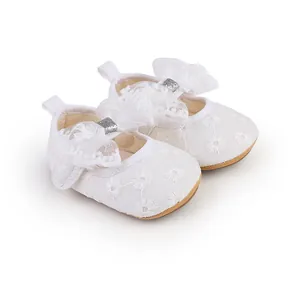 Detailed view of white floral lace baby girl princess shoes with a soft sole and bow