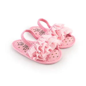 Close-up of cute pink baby walking shoes featuring ruffle trim and polka dot soles.