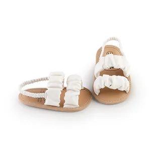 Detailed view of soft white ruffled baby walking sandals with elastic back straps