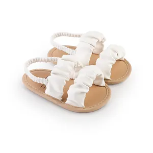 Close-up detail of white ruffled baby girl walking sandals featuring an elastic heel strap