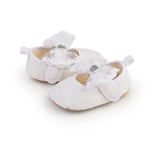 Close-up detail of white lace baby girl princess shoes featuring delicate flower patterns.