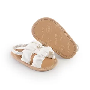 Detailed macro view of white ruffled baby girl prewalker sandals with elastic heel strap
