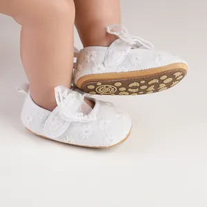 Close-up of white lace baby shoes with daisy embroidery and soft anti-slip soles