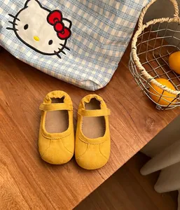 Zapatos de princesa amarillos de ante para niñas pequeñas sobre mesa de madera