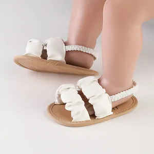 Close-up detail of white cloud-style baby sandals with soft soles and elastic backstraps.