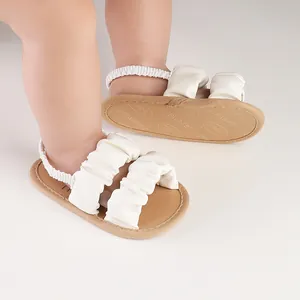 Close-up of white ruffled baby walking sandals with soft non-slip soles.