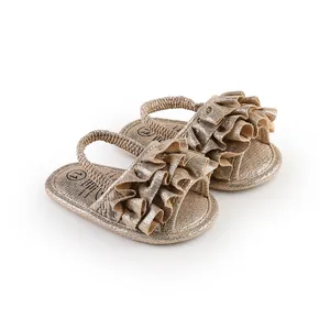 Close-up of gold shimmering baby walking shoes with ruffled straps for 0-1 year olds.
