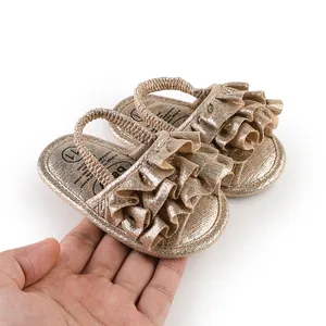 Macro view of shimmering golden ruffled baby pre-walker sandals with elastic strap