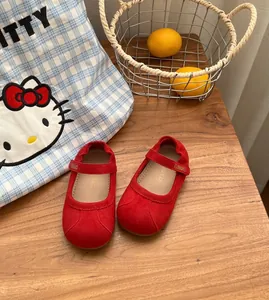 Elegantes zapatos Mary Jane de gamuza roja para niñas con suela blanda en madera.