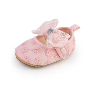 Close-up of pink lace baby girl shoes featuring a large bow and floral embroidery.