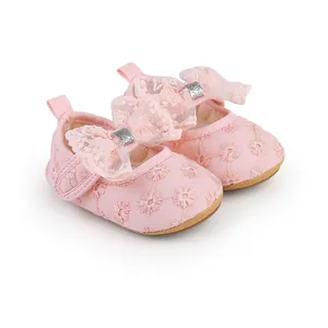 Close-up detail of pink lace baby girl walking shoes with decorative bow and floral embroidery.