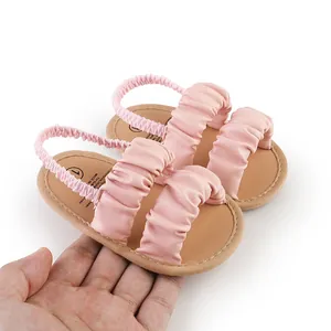 Close-up of pink ruffled baby sandals with soft flexible sole and elastic back strap.